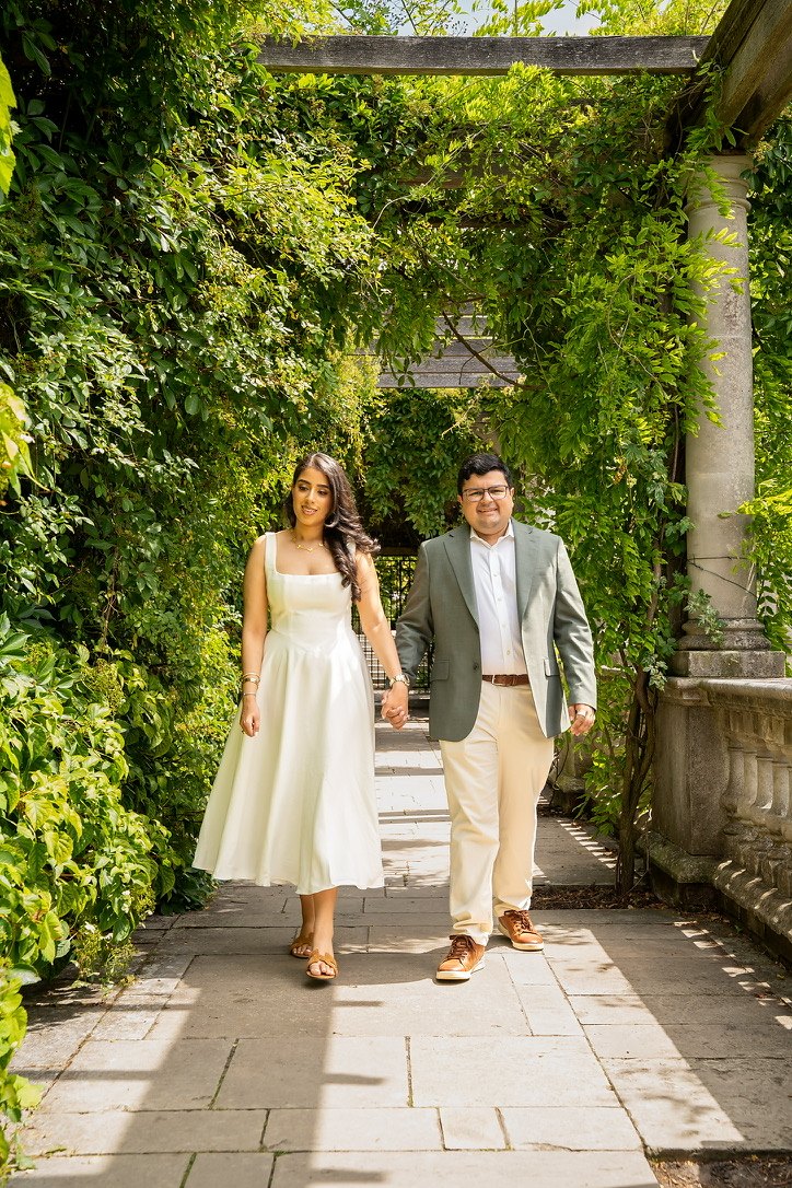 Anaika and Neil walking through a garden arch